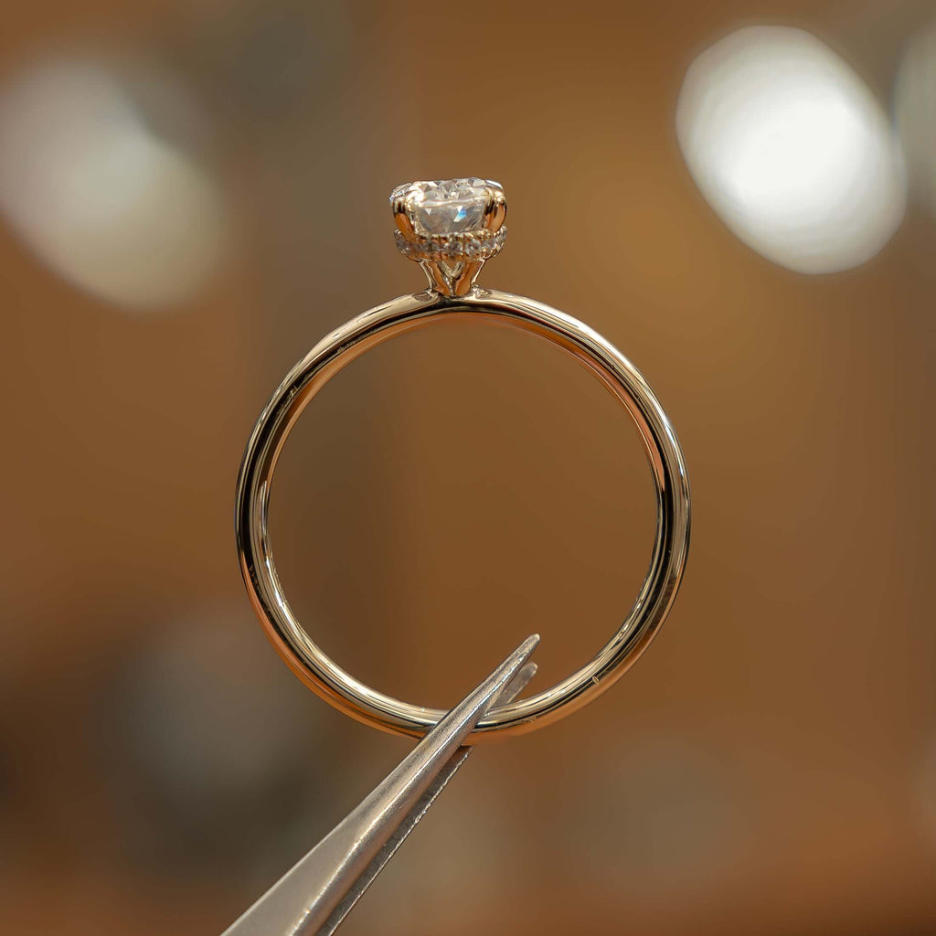 studio image of luxury oval yellow gold hidden halo lab grown diamond engagement ring