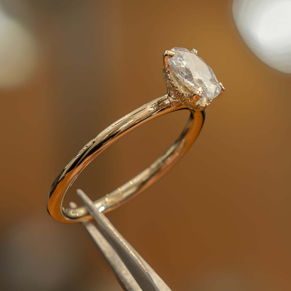 studio shot of luxury oval yellow gold hidden halo lab grown diamond engagement ring