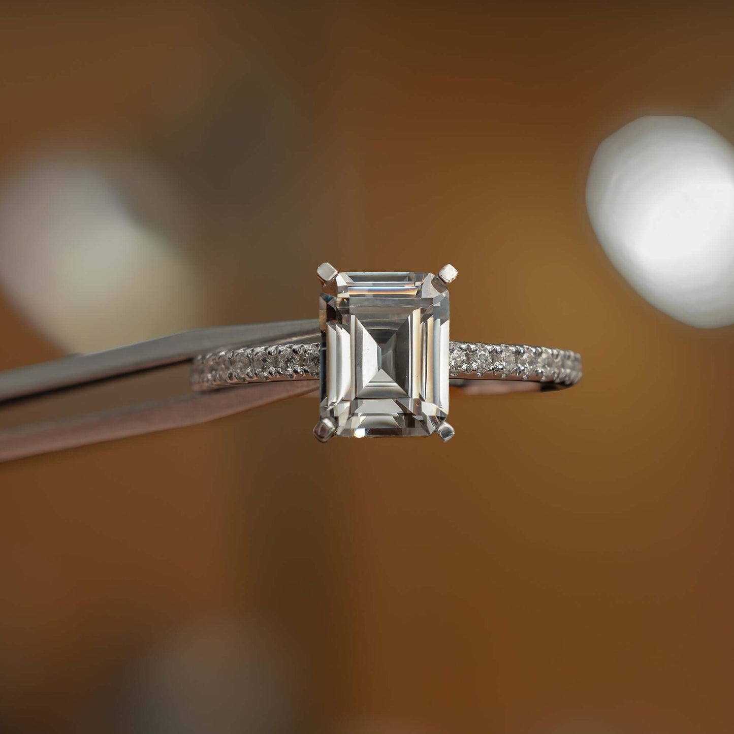 frontal view in studio of luxury emerald platinum diamond set shoulders lab grown diamond engagement ring
