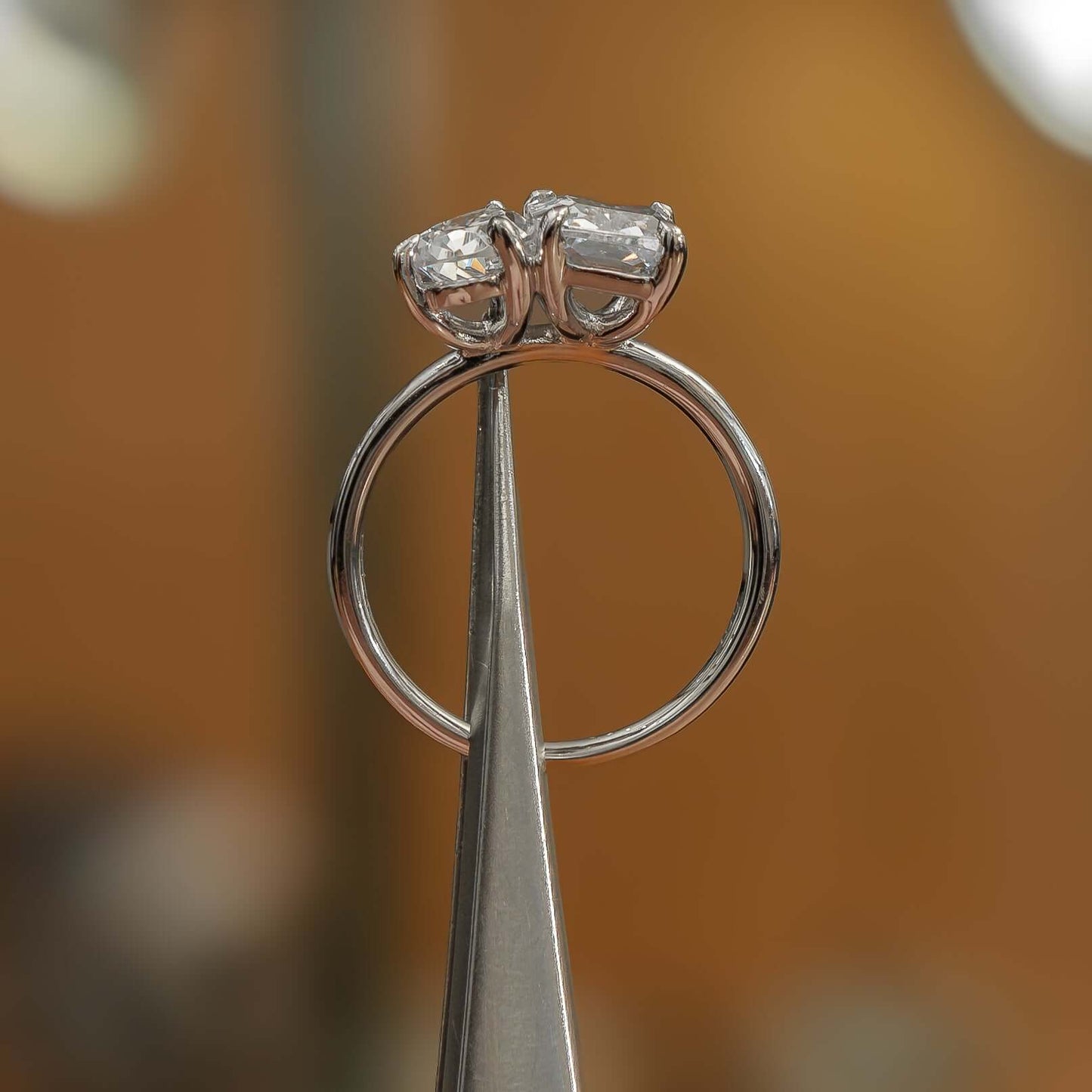 side angle luxury emerald and pear platinum lab grown diamond pair engagement ring in studio