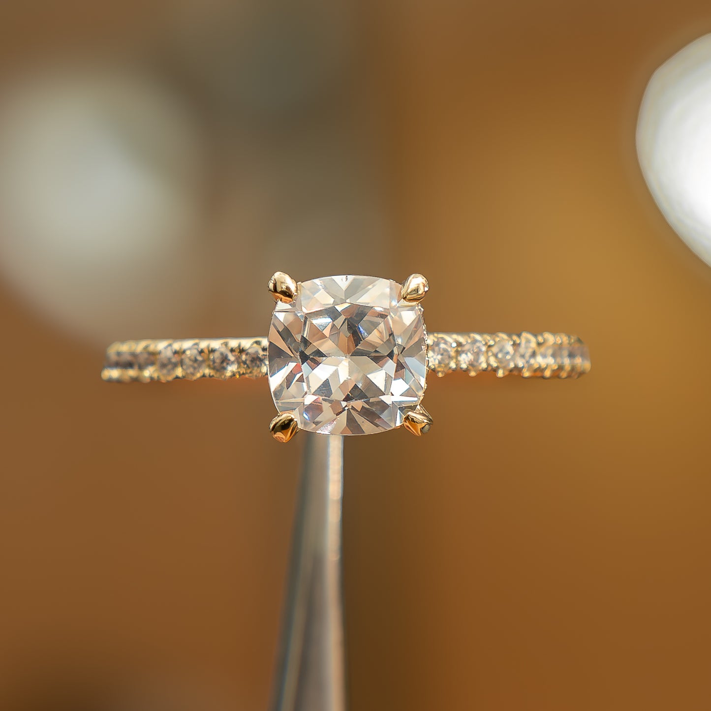 frontal view of luxury cushion yellow gold diamond set shoulders hidden halo lab grown diamond engagement ring